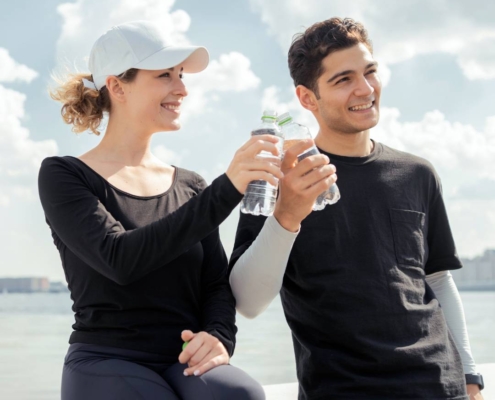 Boy and girl holding a bottle of water, representing hydration and recovery for improved performance in endurance sports with IV therapy.