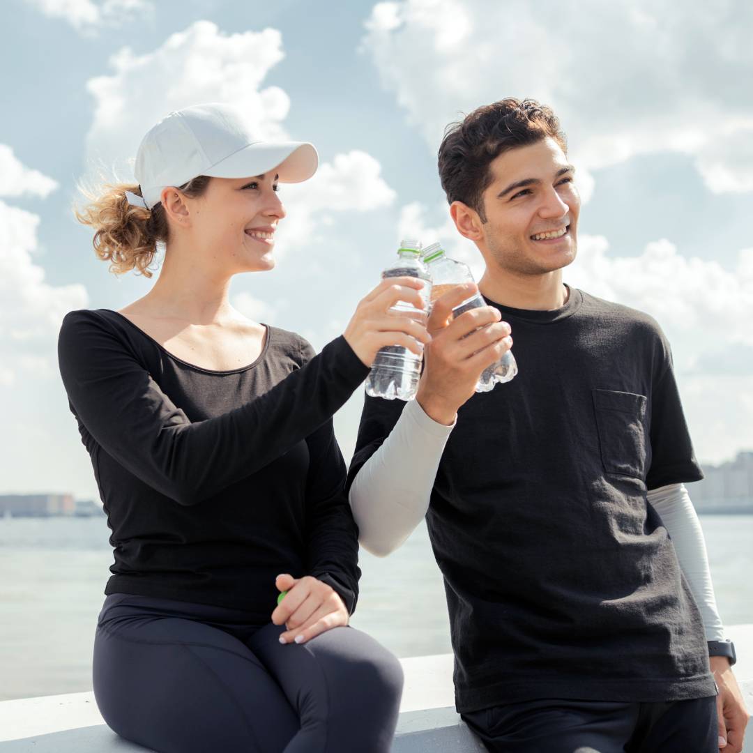 Boy and girl holding a bottle of water, representing hydration and recovery for improved performance in endurance sports with IV therapy.