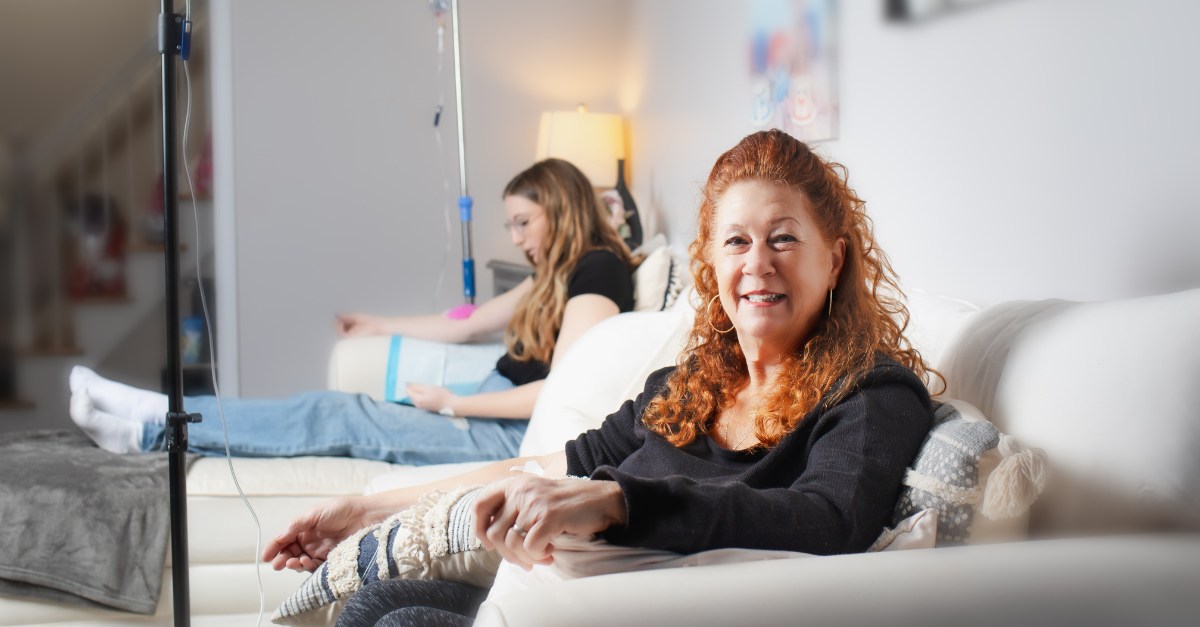Two women receive IV therapy for hangovers in a comfortable living room setting.