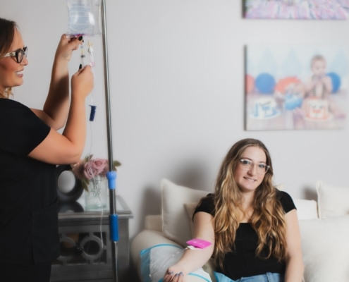 A woman is smiles while receiving iv infusion therapy for migraines from a healthcare professional.