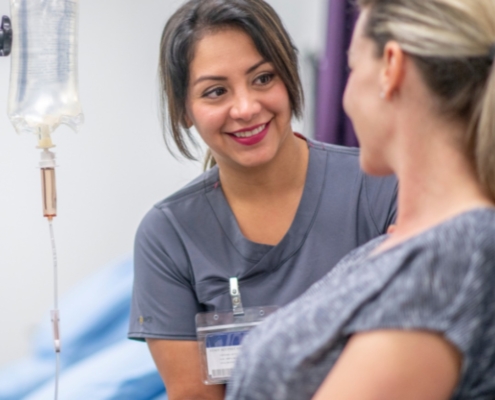 A smiling nurse administering an IV drip to a traveling woman to help skip holiday travel fatigue and treat jet lag.